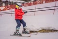 Boy uses a training lift. Child skiing in mountains. Active toddler kid with safety helmet, goggles and poles. Ski race Royalty Free Stock Photo