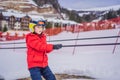 Boy uses a training lift. Child skiing in mountains. Active toddler kid with safety helmet, goggles and poles. Ski race Royalty Free Stock Photo