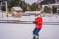 Boy uses a training lift. Child skiing in mountains. Active toddler kid with safety helmet, goggles and poles. Ski race Royalty Free Stock Photo