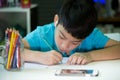 A boy using cellphone and painting on a white paper at home Royalty Free Stock Photo