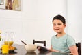 Boy using digital tablet during breakfast in kitchen Royalty Free Stock Photo