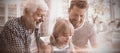 Boy using digital tablet with his father and grandfather in living room Royalty Free Stock Photo