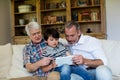 Boy using digital tablet with his father and grandfather in living room Royalty Free Stock Photo