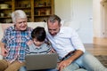 Boy using laptop with his father and grandfather in living room Royalty Free Stock Photo