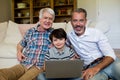 Boy using laptop with his father and grandfather in living room Royalty Free Stock Photo