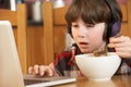 Boy Using Laptop Whilst Eating Breakfast Royalty Free Stock Photo