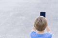 Boy using mobile phone. Child taking photo with his smartphone. Gray urban background. Back view. Technology concept Royalty Free Stock Photo