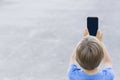 Boy using mobile phone. Child taking photo with his smartphone. Gray urban background. Back view. Technology concept Royalty Free Stock Photo