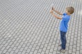 Boy using mobile phone. Child taking photo with his smartphone. Gray urban background. Back view. Technology concept Royalty Free Stock Photo