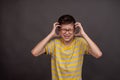 The boy is very emotional and tense, screaming in pain, holding his head. Boy is having panic attack screaming. On a Royalty Free Stock Photo