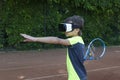 Boy in VR glasses with racquet is preraring to make tennis kick with help of virtual trainer on online lesson.