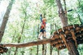 Boy walking across the aerial trail to a wooden platform holding on to the ropes