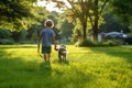 boy walking with a dog on a green summer grassy lawn