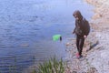 Boy is cathcing frogs and fish on the river using butterfly net.