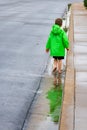 Boy Walking and Splashing in the Gutter of a Street After the Ra