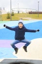 boy in warm clothes jumping on trampoline on modern playground outdoors