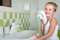 A boy washes his face, wipes her face with a towel in the bathroom.