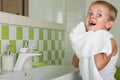 A boy washes his face, wipes her face with a towel in the bathroom.