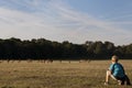 A boy watches a herd of deers in Richmond Park