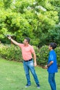 Boy watching his father flying a drone in a countryside scenery