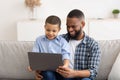 Boy Watching Movie On Tablet Sitting On Dad's Knees Indoors Royalty Free Stock Photo