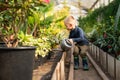 Boy watering flowerpots plants in a greenhouse.