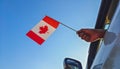 Boy waving Canada flag against the blue sky from the car window close-up shot. Man hand holding Canadian flag