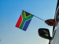 Boy waving South Africa flag against the blue sky from the car window close-up shot. Man hand holding South African flag
