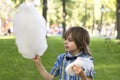 A boy wearing blue shirt with a bow tie eats cotton candy in the park against the backdrop of a lawn Royalty Free Stock Photo