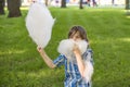 A boy wearing blue shirt with a bow tie eats cotton candy in the park against the backdrop of a lawn Royalty Free Stock Photo