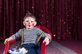 Boy Wearing Clown Makeup Sitting in Chair on Stage Royalty Free Stock Photo
