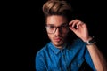 Boy wearing denim posing while fixing his glasses Royalty Free Stock Photo