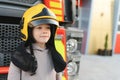 A boy wearing a fireman& x27;s helmet near a fire truck. Royalty Free Stock Photo