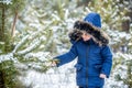 Boy wearing a fur hooded winter coatin the winter forest. Preteen boy having fun playing fresh snowin the winter forest Royalty Free Stock Photo