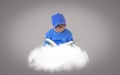 Boy wearing glasses wearing a blue hat, reading book on a cloud that floats in isolated gray background, imaginative concept for