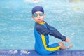 Boy wearing goggles and sit on the edge of the pool. Summer children`s sports activity. Ready to go swimming Freestyle. Looking Royalty Free Stock Photo