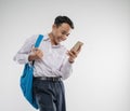 a boy wearing a junior high school uniform looking at a cellphone with an excited gesture with a backpack Royalty Free Stock Photo