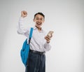 a boy wearing a junior high school uniform smiled happily while holding a cellphone with raise hand Royalty Free Stock Photo