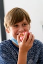 Boy wearing a medical mask eating an apple at school, new normal back to school during pandemic