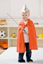 Boy wearing paper hat, cape and carrying a sword