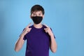 Boy wearing protective mask on light blue background. Child safety Royalty Free Stock Photo