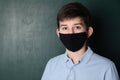 Boy wearing mask near chalkboard, space for text. Child safety Royalty Free Stock Photo