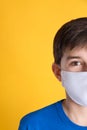 Boy wearing protective mask on yellow background, closeup. Child safety Royalty Free Stock Photo
