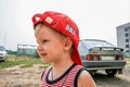 A boy wearing red baseball cap by the car, side view. Royalty Free Stock Photo
