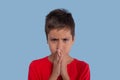 The boy wearing red shirt is very upset or angry on blue back Royalty Free Stock Photo