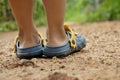 Boy wearing sandals on dirt road.