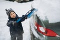 boy wearing scandinavian knit hat helping to brush snow from a car