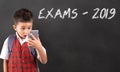 Boy wearing school uniform looking at cell phone with shocked expression on his face. Royalty Free Stock Photo