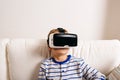 Boy wearing virtual reality goggles. Studio shot, white couch Royalty Free Stock Photo