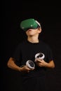 Boy wearing VR headset looking upward while interacting with virtual content in a dark studio setting Royalty Free Stock Photo